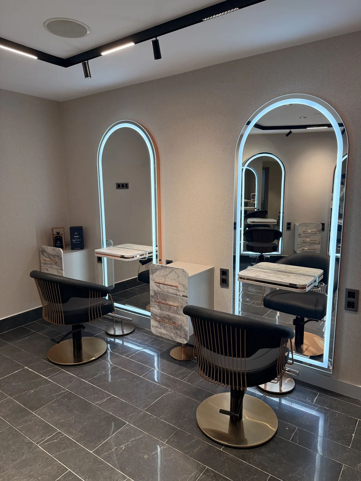 Élite Coiffeur Taksim kuaför — aydınlatmalı kemerli aynalar ve koltuklar